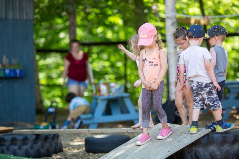 Enfants qui jouent sur une planche dans la cour du service de garde