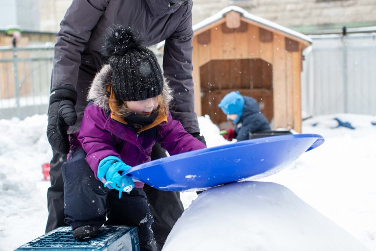 Éducatrice qui aide un enfant à glisser dans la neige