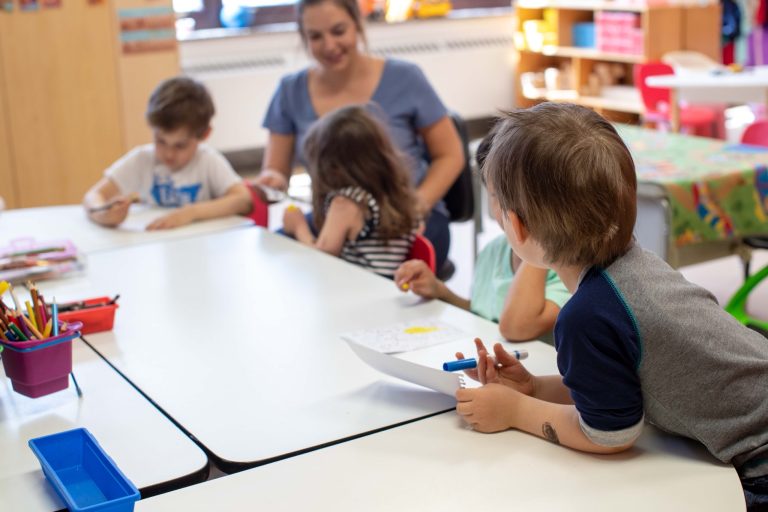 Éducatrice et enfants en activité de dessin à la table