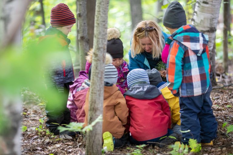 Éducatrice et groupe d'enfants assis en forêt